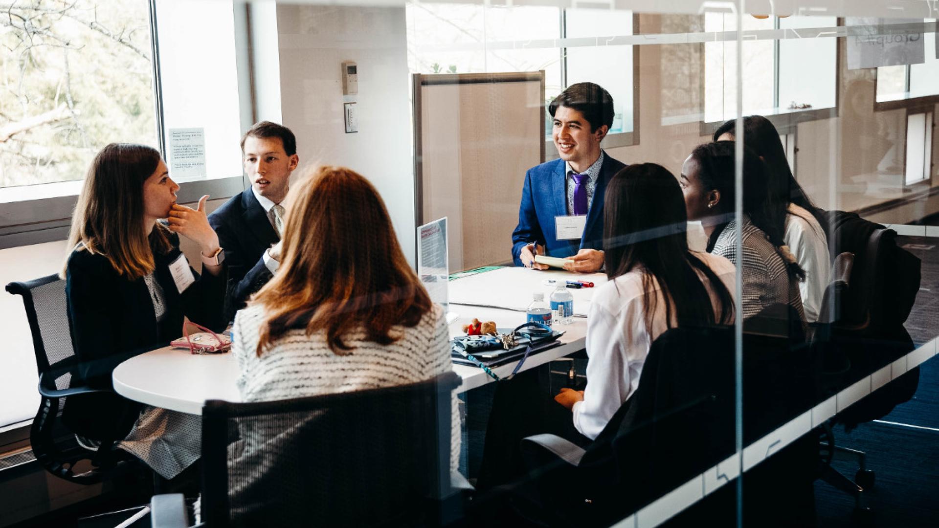 坐在房间里的男性和女性学生在桌上互相谈话