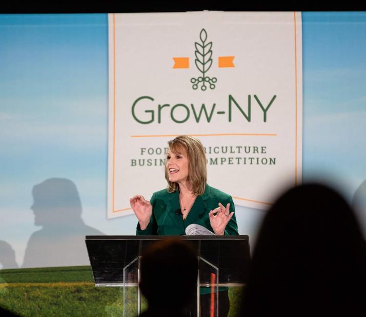 一位妇女在一个成长标志前对人群讲话。