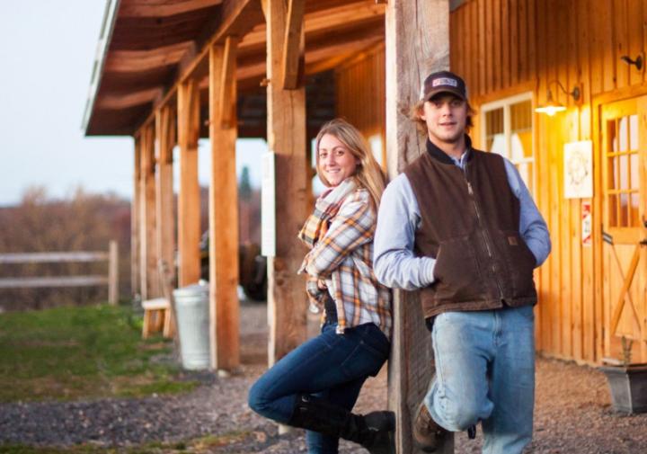 站立在谷仓前面的一个男人和妇女有一条腿的一条腿撑对杆