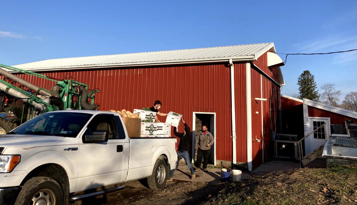 人们在一辆卡车的箱子在谷仓前面