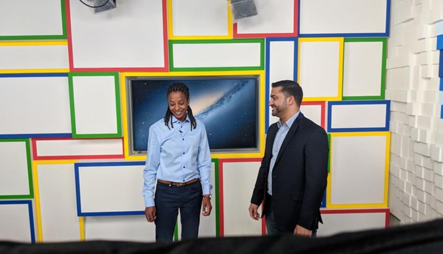 一个年轻女子在谷歌的房间里旁边站在一个男人旁边